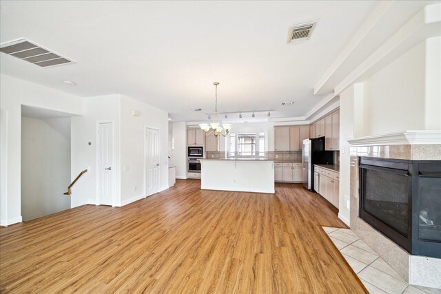 2402 Calumet St Unit C, Houston, TX 77004 - kitchen with a tiled fireplace, stainless steel appliances, a chandelier, light wood-style flooring, and tasteful backsplash