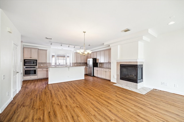 2402 Calumet St Unit C, Houston, TX 77004 - kitchen featuring appliances with stainless steel finishes, open floor plan, a chandelier, wood finished floors, and backsplash