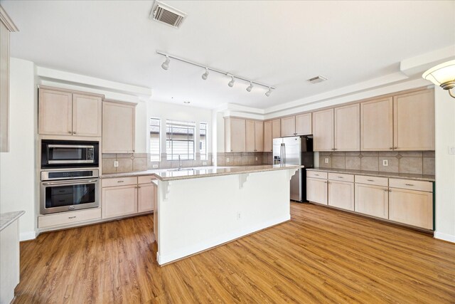 2402 Calumet St Unit C, Houston, TX 77004 - kitchen featuring appliances with stainless steel finishes, light brown cabinetry, a breakfast bar, and light wood finished floors