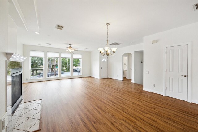 2402 Calumet St Unit C, Houston, TX 77004 - unfurnished living room featuring a tiled fireplace, a ceiling fan, light wood-style flooring, a chandelier, and arched walkways