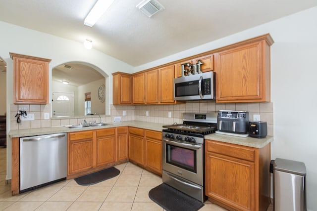 1803 Fallow Ln, Houston, TX 77049 - kitchen featuring appliances with stainless steel finishes, a sink, decorative backsplash, light countertops, and arched walkways