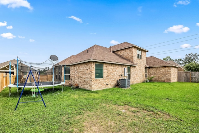 12510 Sherborne Castle Ct, Tomball, TX 77375 - back of property featuring a trampoline, brick siding, central AC unit, and a shingled roof
