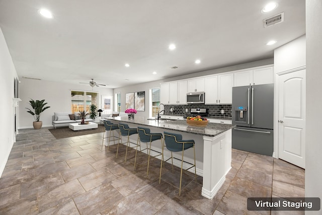 12510 Sherborne Castle Ct, Tomball, TX 77375 - kitchen with stainless steel appliances, a sink, a breakfast bar area, tasteful backsplash, and white cabinets