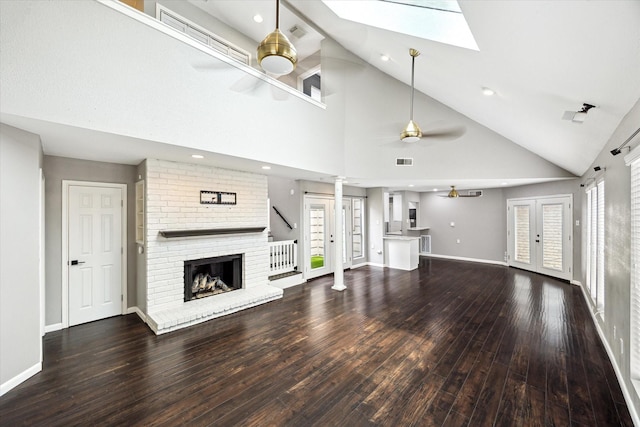 12625 Memorial Dr Unit 65, Houston, TX 77024 - unfurnished living room with ceiling fan, hardwood / wood-style flooring, a skylight, a brick fireplace, and high vaulted ceiling