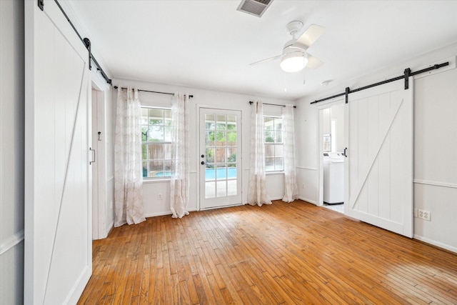 1219 Candlelight Ln, Houston, TX 77018 - unfurnished bedroom featuring a barn door, washer / clothes dryer, wood-type flooring, and access to outside