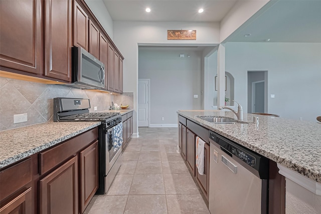 18526 Waterfall Creek Way, Cypress, TX 77429 - kitchen featuring appliances with stainless steel finishes, a sink, backsplash, light stone counters, and recessed lighting
