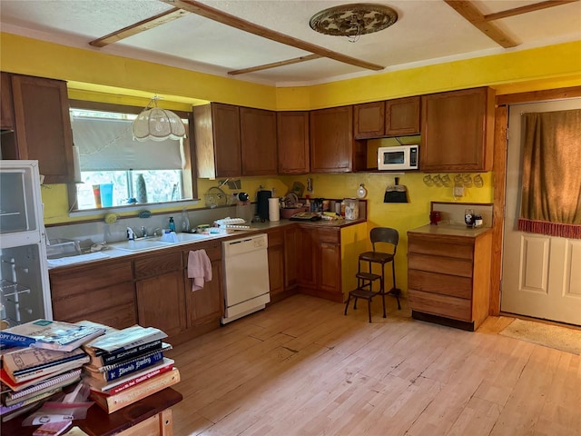 385 Ole Long Pull Rd, Livingston, TX 77351 - kitchen featuring white appliances, light wood-style flooring, a sink, and brown cabinetry