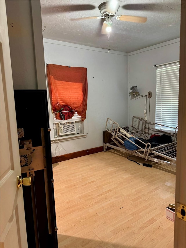 385 Ole Long Pull Rd, Livingston, TX 77351 - bedroom featuring wood finished floors, a textured ceiling, cooling unit, a ceiling fan, and baseboards