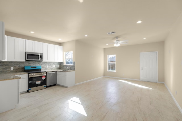 7754 Ave J, Houston, TX 77012 - kitchen with appliances with stainless steel finishes, tasteful backsplash, a sink, white cabinets, and recessed lighting