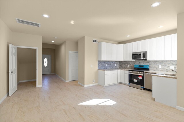 7754 Ave J, Houston, TX 77012 - kitchen featuring stainless steel appliances, a sink, light stone countertops, tasteful backsplash, and white cabinets