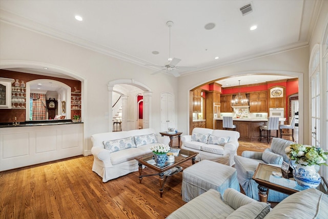 10911 Kemwood Dr, Houston, TX 77024 - living room with arched walkways, crown molding, a ceiling fan, light wood-type flooring, and recessed lighting