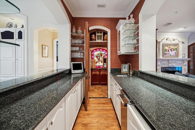 10911 Kemwood Dr, Houston, TX 77024 - kitchen with a sink, white cabinetry, ornamental molding, dark stone counters, and light wood finished floors