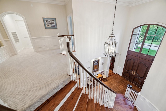 10911 Kemwood Dr, Houston, TX 77024 - entryway featuring arched walkways, a chandelier, ornamental molding, a decorative wall, and wood finished floors
