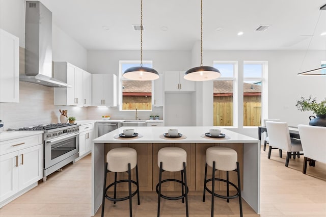 819 Dorothy St Unit B, Houston, TX 77008 - kitchen with wall chimney exhaust hood, appliances with stainless steel finishes, tasteful backsplash, a center island, and white cabinetry