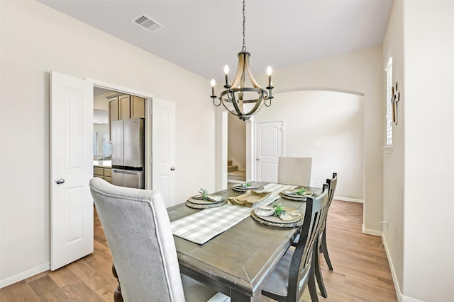 13823 Pointed Edge Ln, Cypress, TX 77429 - dining area with arched walkways, a chandelier, baseboards, light wood-style flooring, and stairs