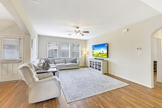 13823 Pointed Edge Ln, Cypress, TX 77429 - living room featuring arched walkways, ceiling fan, light wood finished floors, and baseboards