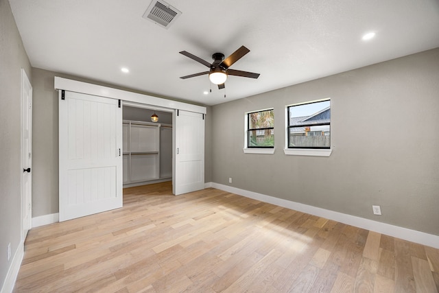 1931 Chaparral Dr, Houston, TX 77043 - unfurnished bedroom featuring baseboards, light wood-style flooring, recessed lighting, ceiling fan, and a barn door