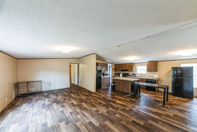 17968 County Road 426, Brazoria, TX 77422 - kitchen with freestanding refrigerator, dark wood-style flooring, a textured ceiling, light countertops, and brown cabinets