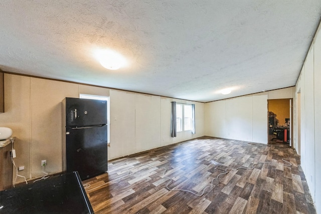 17968 County Road 426, Brazoria, TX 77422 - unfurnished living room featuring wood finished floors, a decorative wall, and a textured ceiling
