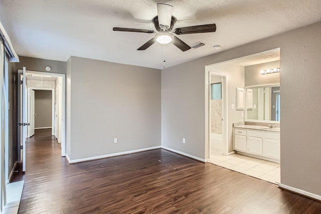 5607 Circlegate Dr, Spring, TX 77373 - unfurnished bedroom with wood finished floors, baseboards, connected bathroom, a sink, and a textured ceiling