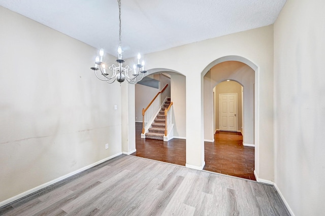 1752 Cypress Meadows Dr, Dickinson, TX 77539 - unfurnished dining area featuring wood finished floors, a chandelier, baseboards, arched walkways, and stairway