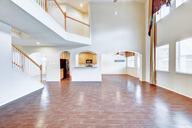 1752 Cypress Meadows Dr, Dickinson, TX 77539 - unfurnished living room with a ceiling fan, a towering ceiling, dark wood-style flooring, stairway, and baseboards