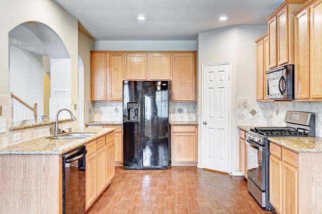 1752 Cypress Meadows Dr, Dickinson, TX 77539 - kitchen with black appliances, light brown cabinetry, a sink, light stone countertops, and recessed lighting