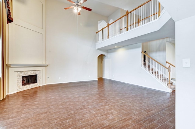1752 Cypress Meadows Dr, Dickinson, TX 77539 - unfurnished living room featuring a high ceiling, ceiling fan, stairs, arched walkways, and a high end fireplace