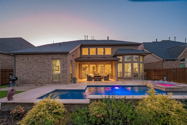 27815 Carol Collier Ct, Katy, TX 77494 - back of property at dusk featuring a pool with connected hot tub, a fenced backyard, brick siding, and a patio area