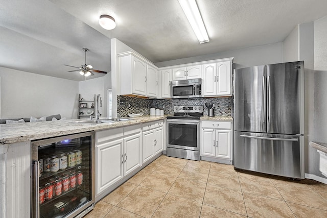 3902 Cary Creek Dr, Baytown, TX 77521 - kitchen with stainless steel appliances, wine cooler, open floor plan, a sink, and white cabinetry