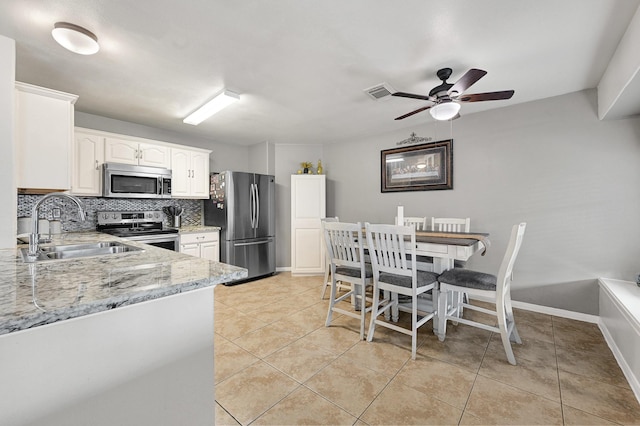 3902 Cary Creek Dr, Baytown, TX 77521 - kitchen with appliances with stainless steel finishes, a sink, backsplash, light stone counters, and light tile patterned floors