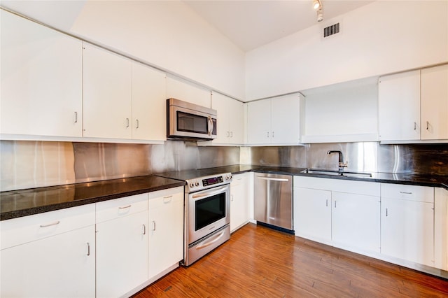 14 Greenway Plz Unit 19P, Houston, TX 77046 - kitchen with appliances with stainless steel finishes, backsplash, dark countertops, and white cabinets