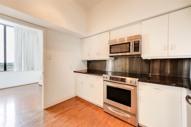 14 Greenway Plz Unit 19P, Houston, TX 77046 - kitchen featuring stainless steel appliances, backsplash, dark countertops, and light wood-type flooring