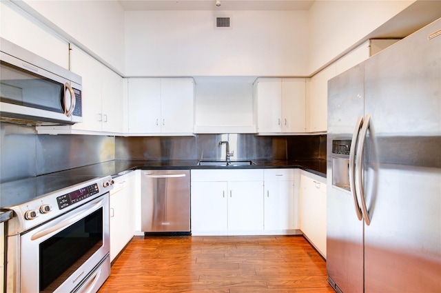 14 Greenway Plz Unit 19P, Houston, TX 77046 - kitchen featuring appliances with stainless steel finishes, dark countertops, tasteful backsplash, light wood finished floors, and white cabinetry