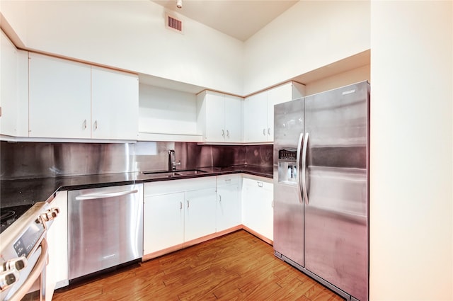 14 Greenway Plz Unit 19P, Houston, TX 77046 - kitchen with appliances with stainless steel finishes, dark countertops, backsplash, light wood finished floors, and white cabinets