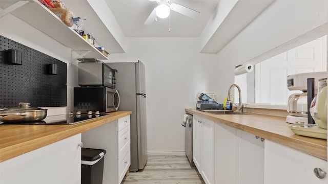 212 Plaza Verde Dr Unit F-22, Houston, TX 77038 - kitchen with wooden counters, appliances with stainless steel finishes, a sink, light wood finished floors, and white cabinetry