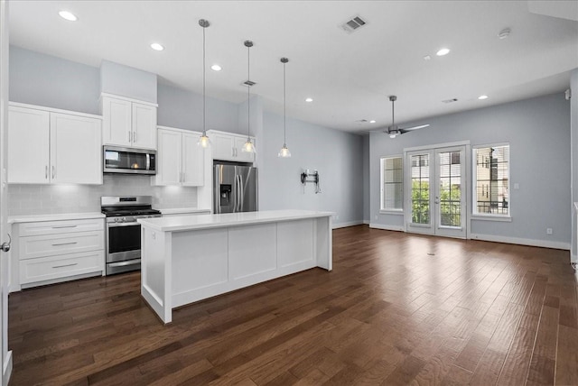 2607 Mcilhenny St, Houston, TX 77004 - kitchen featuring appliances with stainless steel finishes, decorative backsplash, white cabinets, a kitchen island, and light countertops