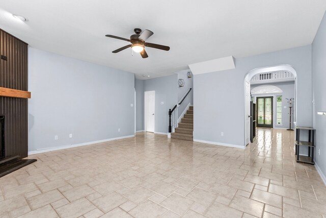 3815 Griffin Ln, Missouri City, TX 77459 - unfurnished living room with ceiling fan, stairs, a fireplace, arched walkways, and baseboards