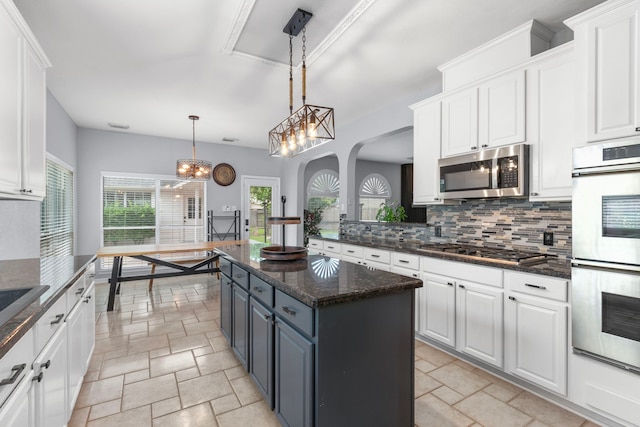 3815 Griffin Ln, Missouri City, TX 77459 - kitchen with appliances with stainless steel finishes, white cabinets, decorative backsplash, stone tile flooring, and arched walkways
