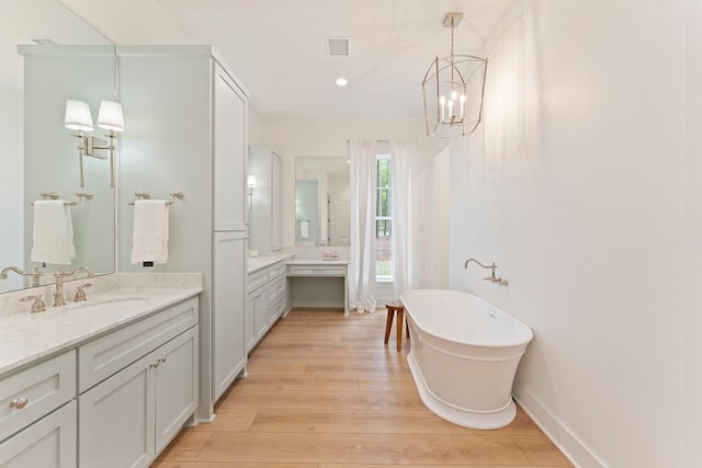 567 Lonestar Rd, Huntsville, TX 77340 - bathroom featuring two vanities, a freestanding tub, wood finished floors, a chandelier, and recessed lighting