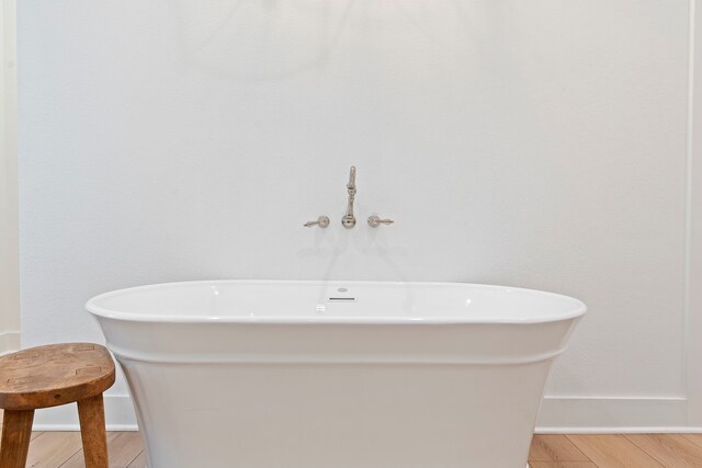567 Lonestar Rd, Huntsville, TX 77340 - full bath featuring baseboards, a freestanding tub, and wood finished floors