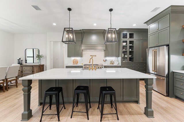567 Lonestar Rd, Huntsville, TX 77340 - kitchen with high end refrigerator, custom exhaust hood, backsplash, light wood finished floors, and pendant lighting