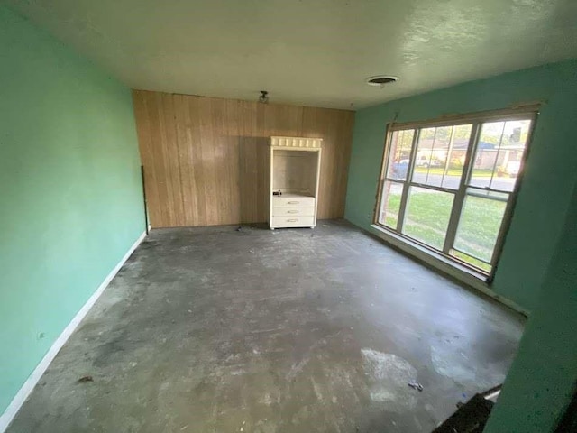 3200 4th Ave, Port Arthur, TX 77642 - unfurnished living room featuring wooden walls, unfinished concrete floors, and baseboards