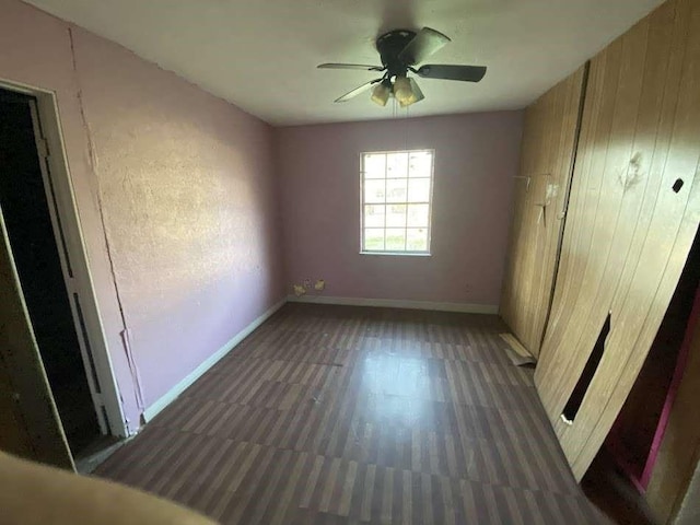 3200 4th Ave, Port Arthur, TX 77642 - unfurnished bedroom with baseboards, wood walls, ceiling fan, and wood finished floors