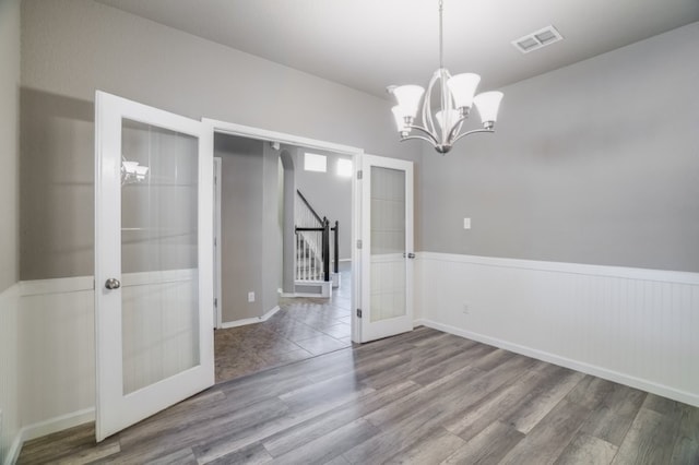 6763 Indian Ldg, San Antonio, TX 78253 - unfurnished dining area featuring french doors, wood finished floors, a wainscoted wall, a chandelier, and stairs