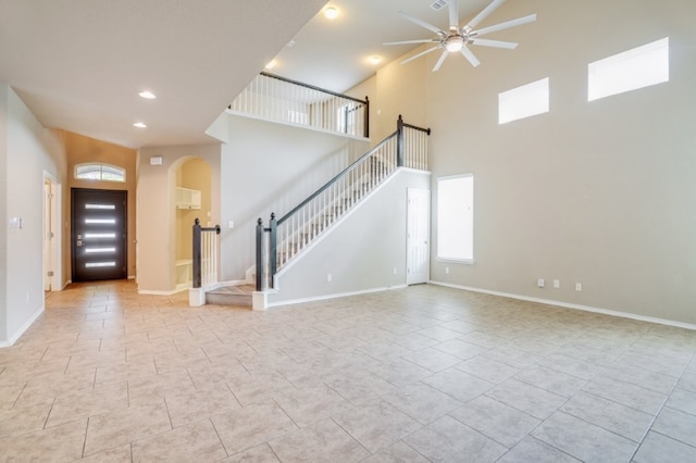 6763 Indian Ldg, San Antonio, TX 78253 - unfurnished living room with ceiling fan, stairs, arched walkways, a high ceiling, and baseboards