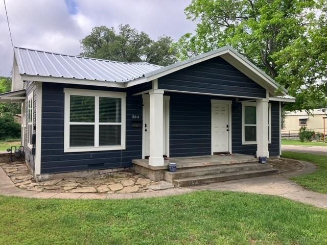 204 E Dry St, San Saba, TX 76877 - view of front of property with metal roof, covered porch, and a front lawn