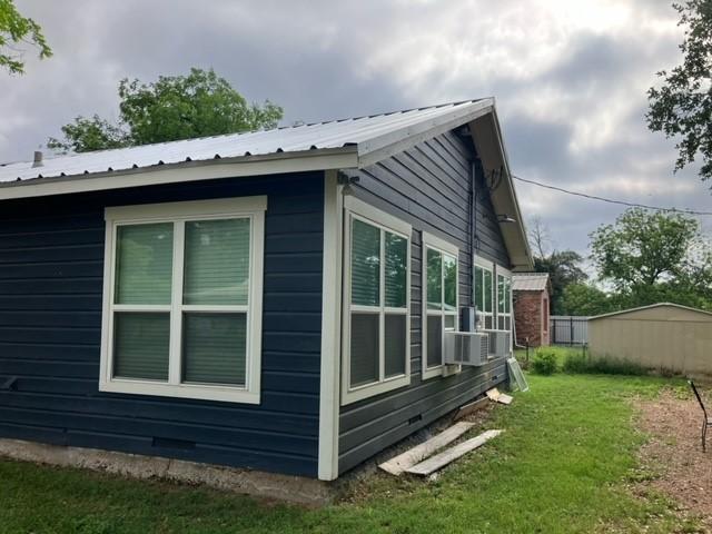 204 E Dry St, San Saba, TX 76877 - view of home's exterior with metal roof and a lawn
