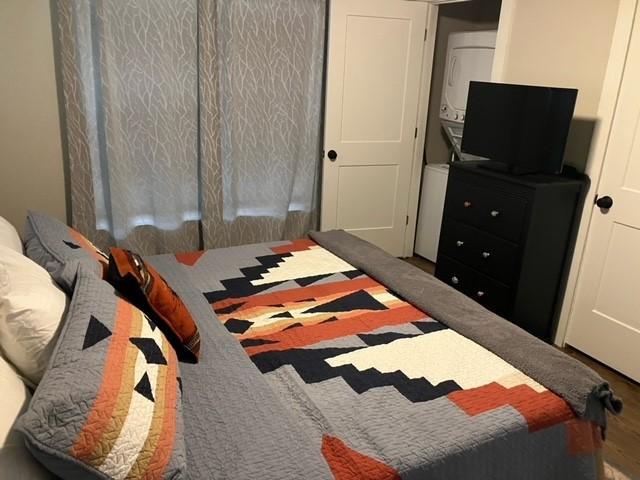 204 E Dry St, San Saba, TX 76877 - bedroom with stacked washer / drying machine and wood finished floors