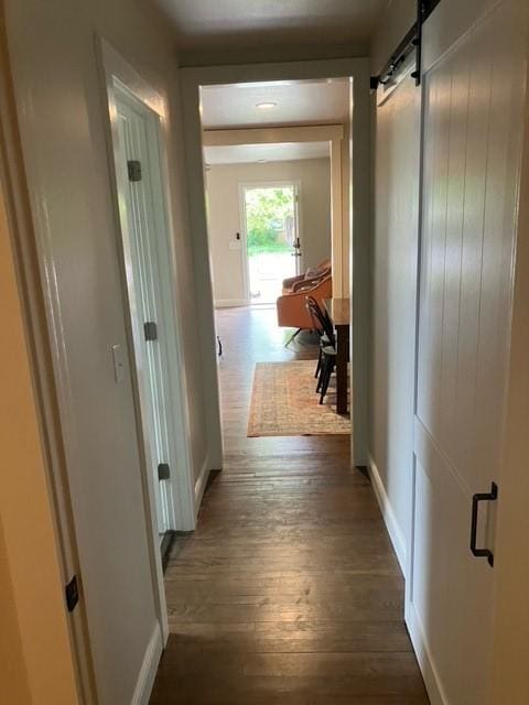 204 E Dry St, San Saba, TX 76877 - corridor with dark wood-style floors, a barn door, and baseboards